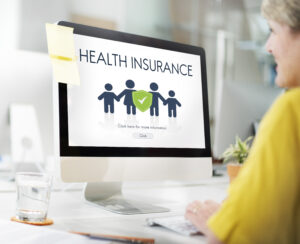 A senior woman working on a computer to maximize health insurance benefits.