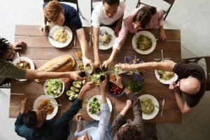 People around a table raising their glasses in a toast before the meal.
